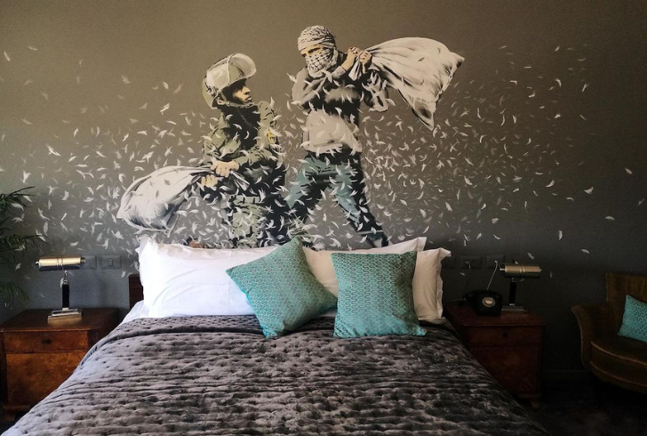 Banksy's exhibitions, like "The Walled Off Hotel," draw global crowds. How does Banksy profit from these ventures?